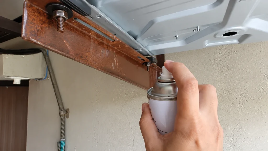 Spraying Maintenance Spray on Rusty Appliance Bracket